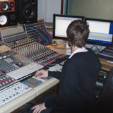 Aron Arnarsson the recording engineer messing with sliders on the mixing console in the control room of Studio Sundlaugin