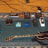 Guitar effects and a Les Paul guitar on the floor with four guitar amplifiers in the background at Studio Hljóðriti